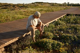 ein Mann sitzt auf einer Holzbrücke auf einem Feld