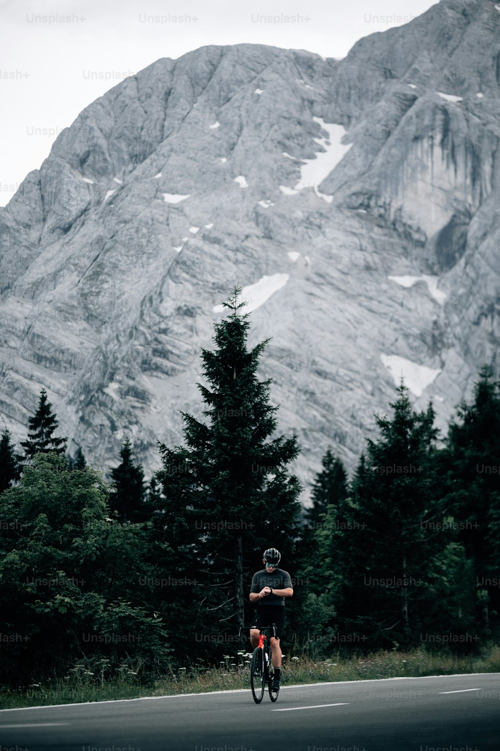 a man riding a bike down a road in front of a mountain