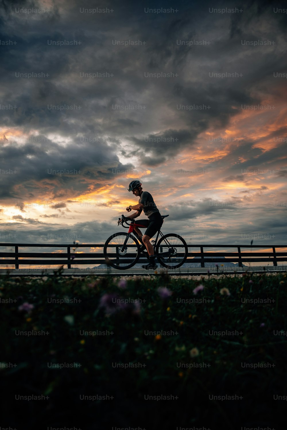 a man riding a bike down a road under a cloudy sky