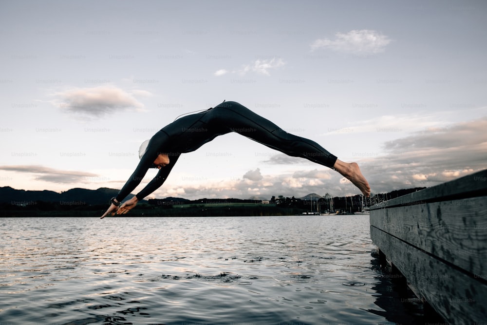 a man doing a handstand on the edge of a body of water