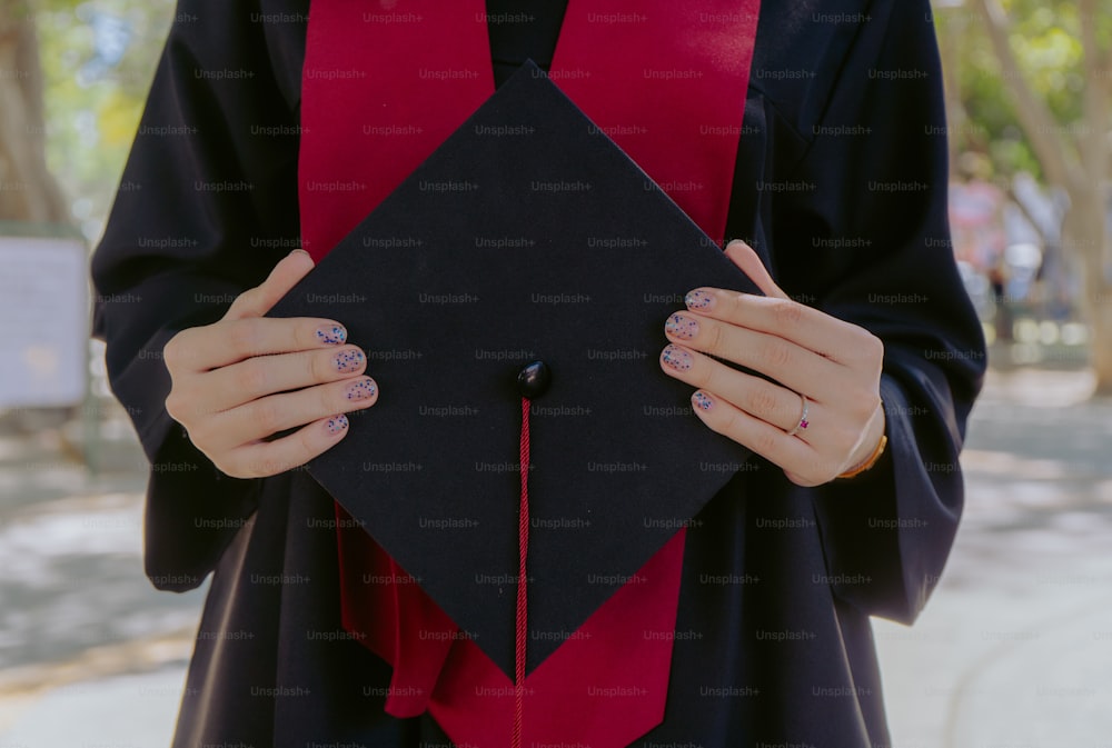 a woman in a graduation gown holding a black square