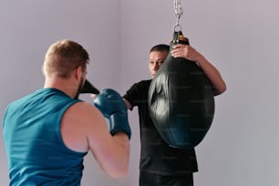 a man holding a punching bag in front of another man