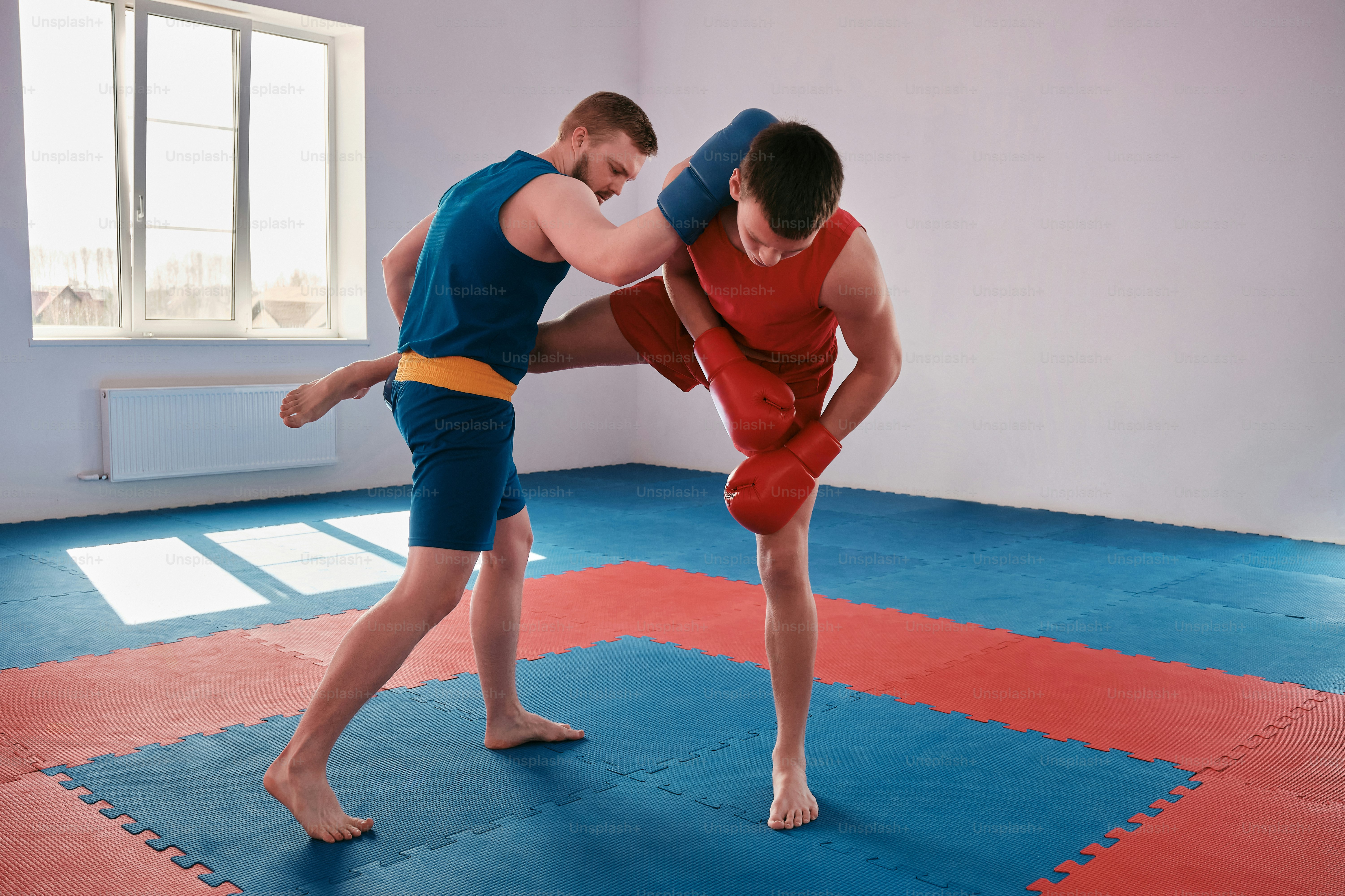 A couple of men standing on top of a blue mat photo – Wushu Image on ...