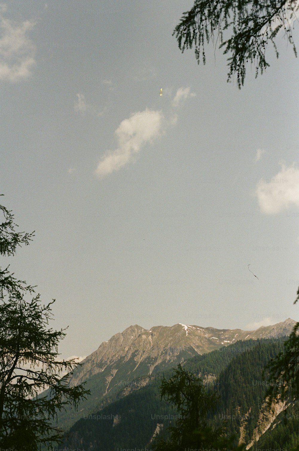uma vista de uma montanha com uma pipa voando no céu