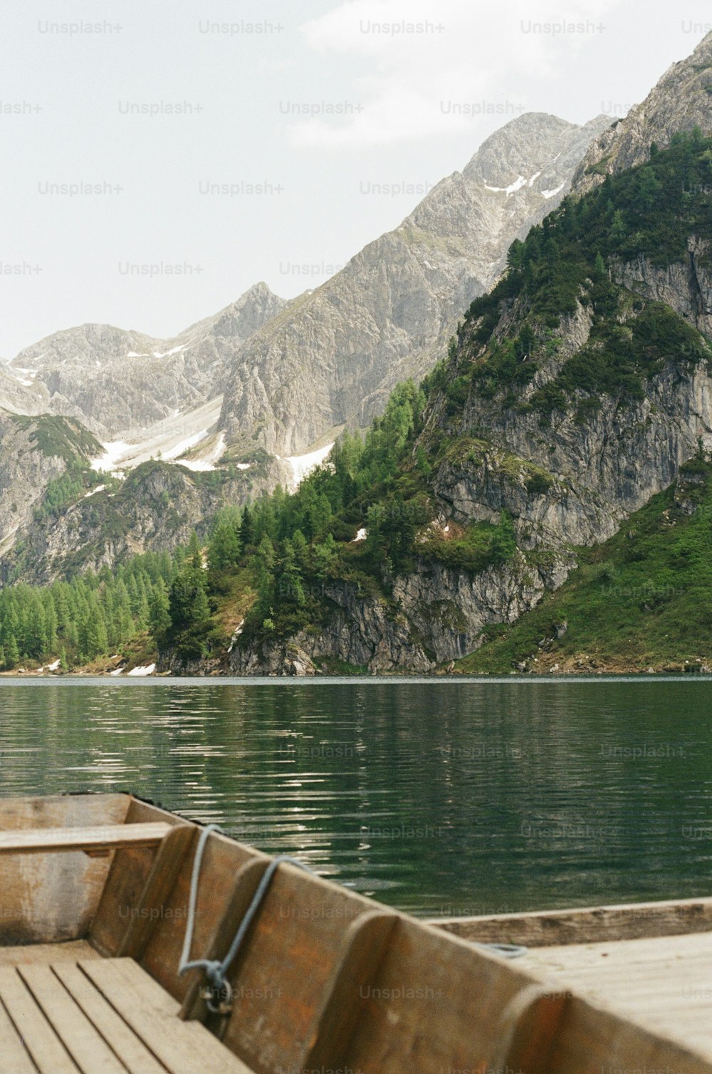 a wooden boat on a lake with mountains in the background