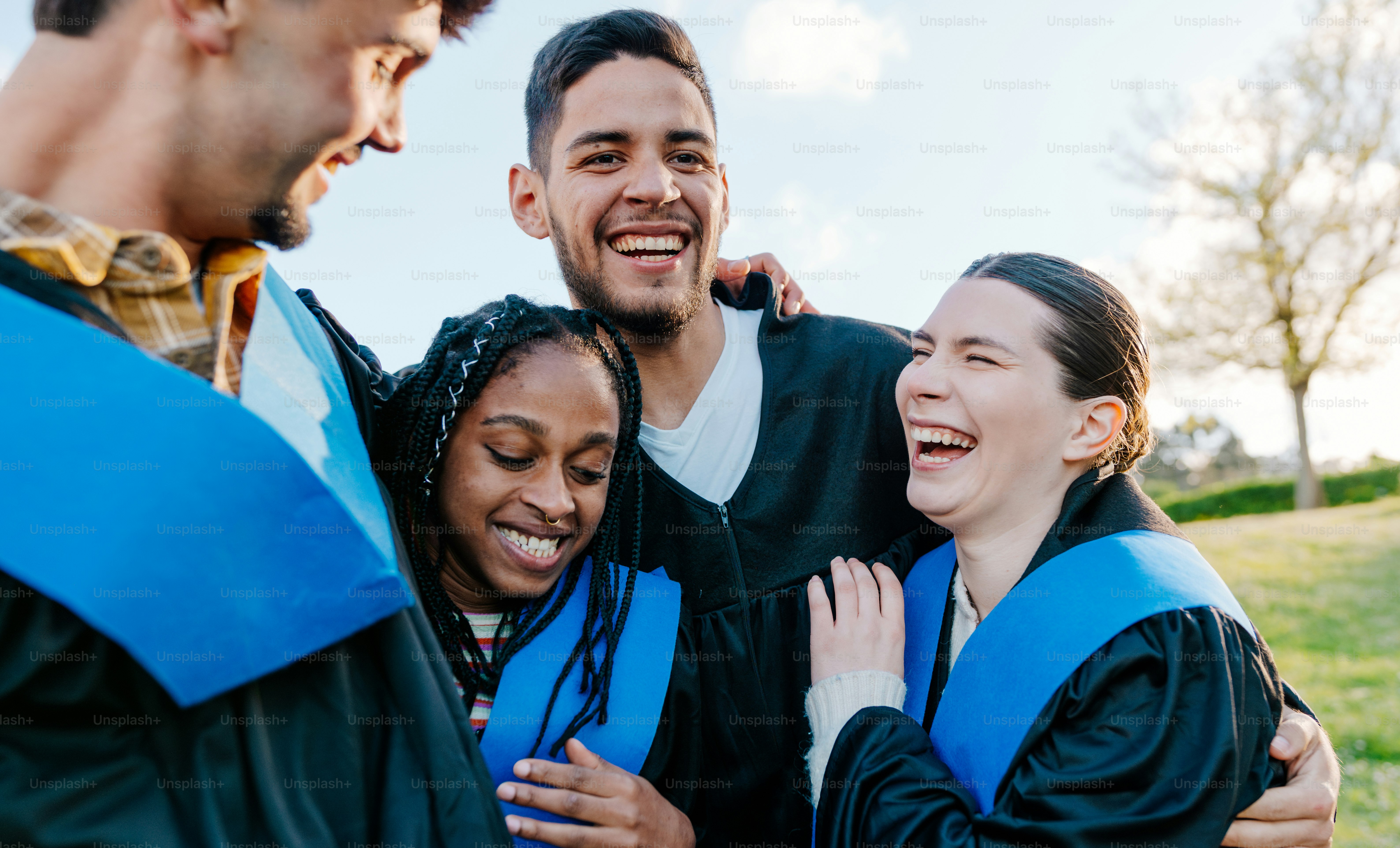 Formandos em trajes acadêmicos rindo juntos ao ar livre