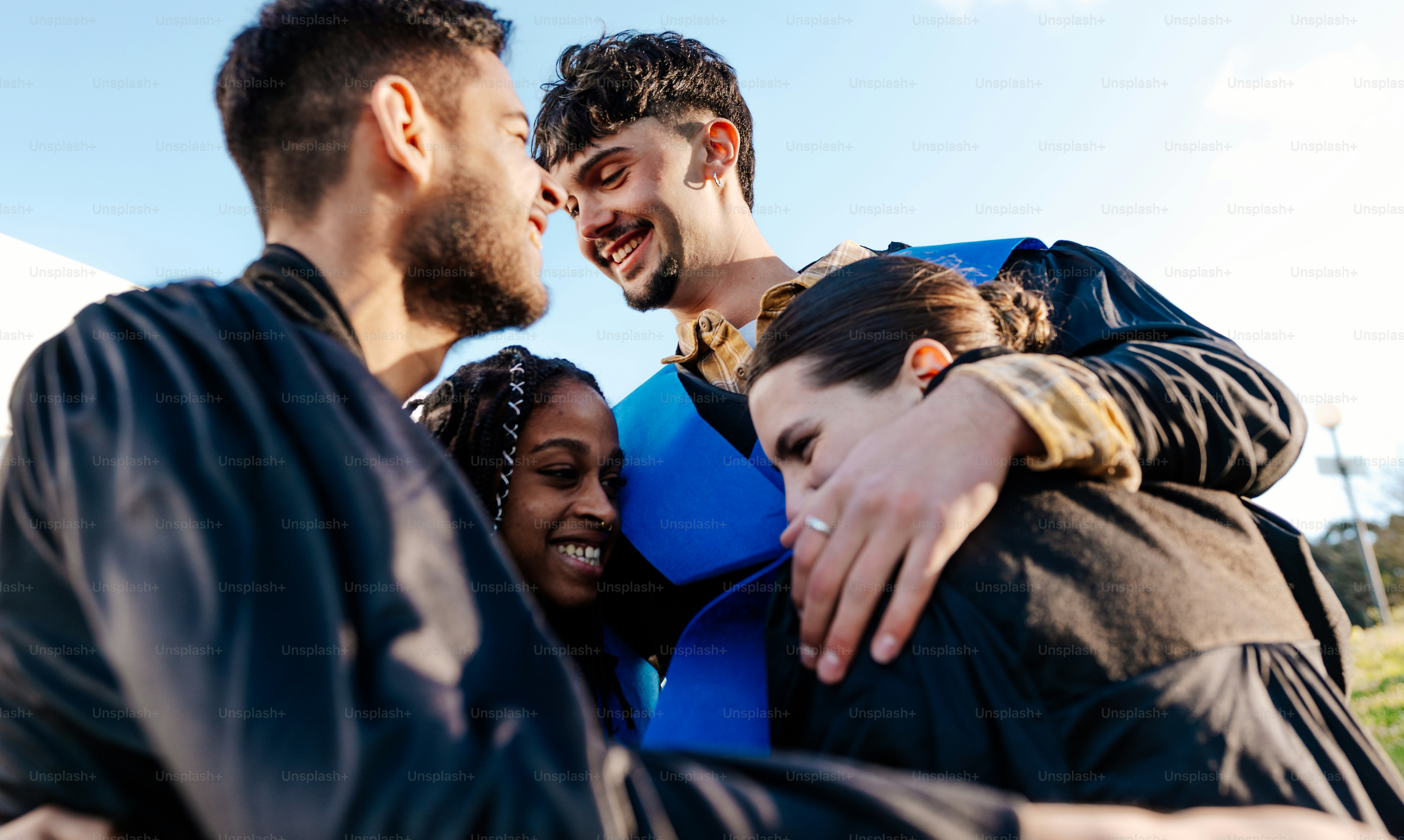 Quatro amigos se abraçando e sorrindo ao ar livre