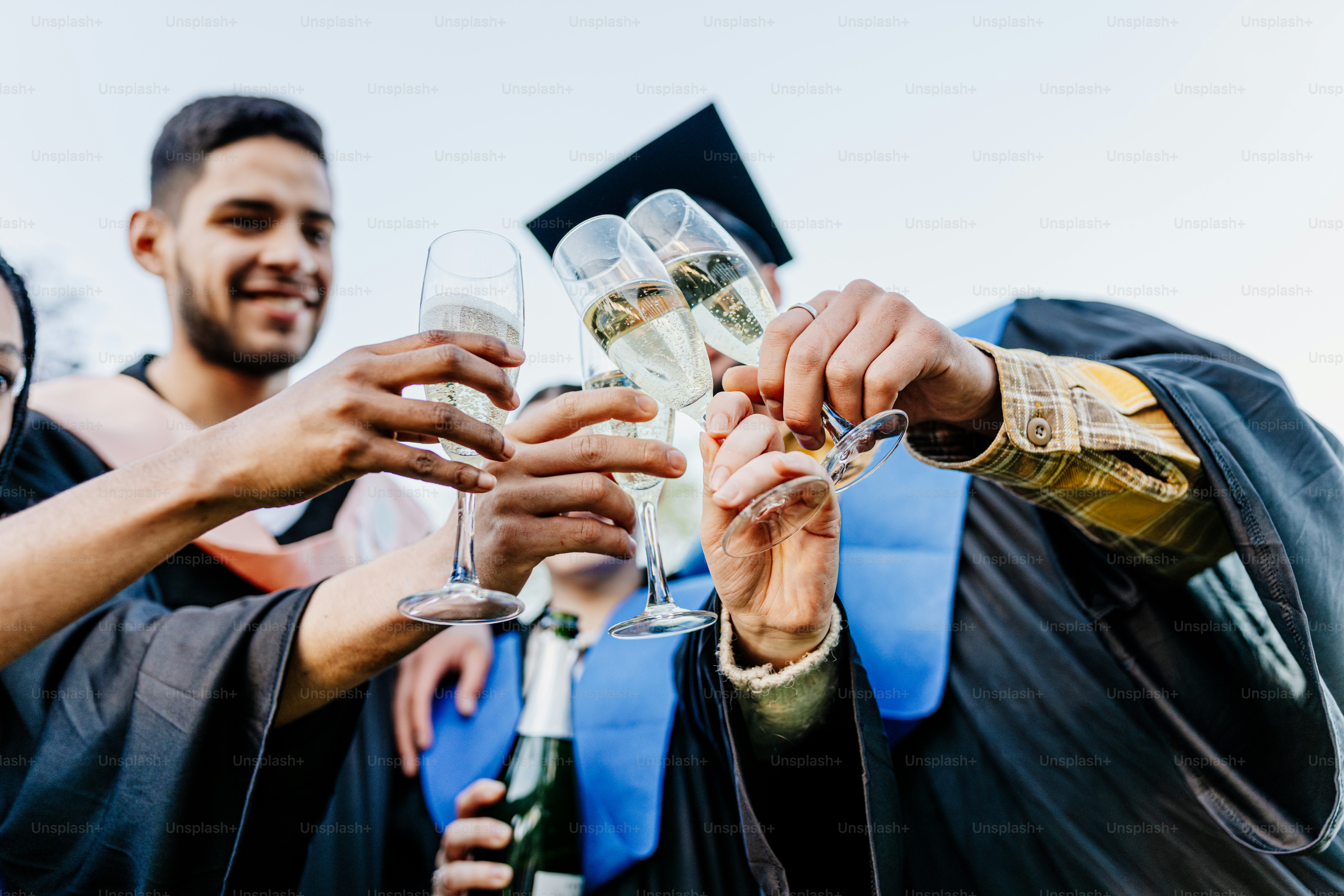 Formandos de toga e touca brindam com taças de champanhe