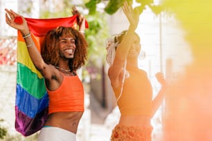 a couple of women standing next to each other holding a rainbow flag