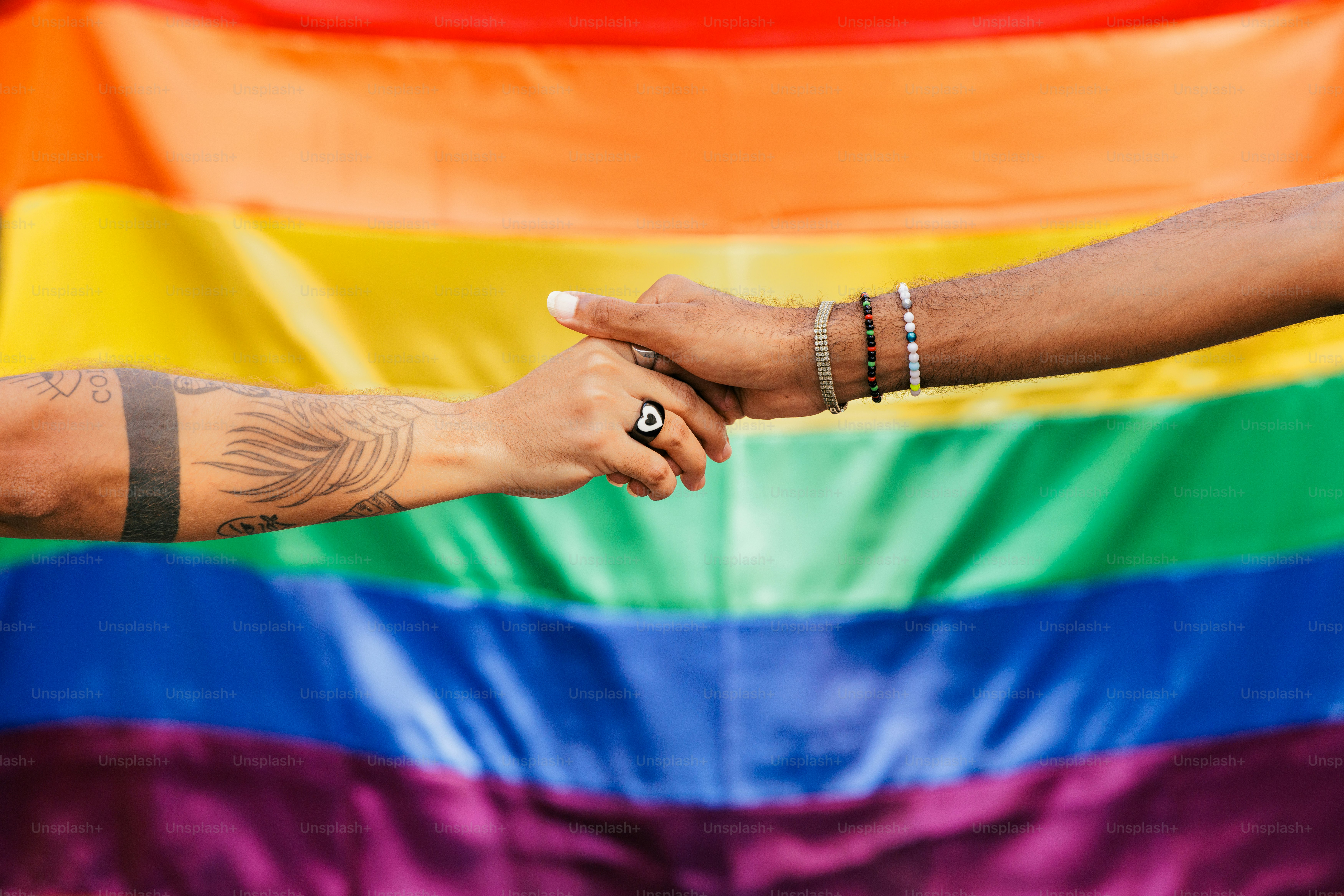 Un homme et une femme se tenant la main devant un drapeau arc-en-ciel