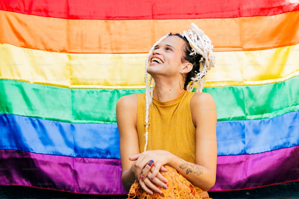 a woman sitting in front of a rainbow flag