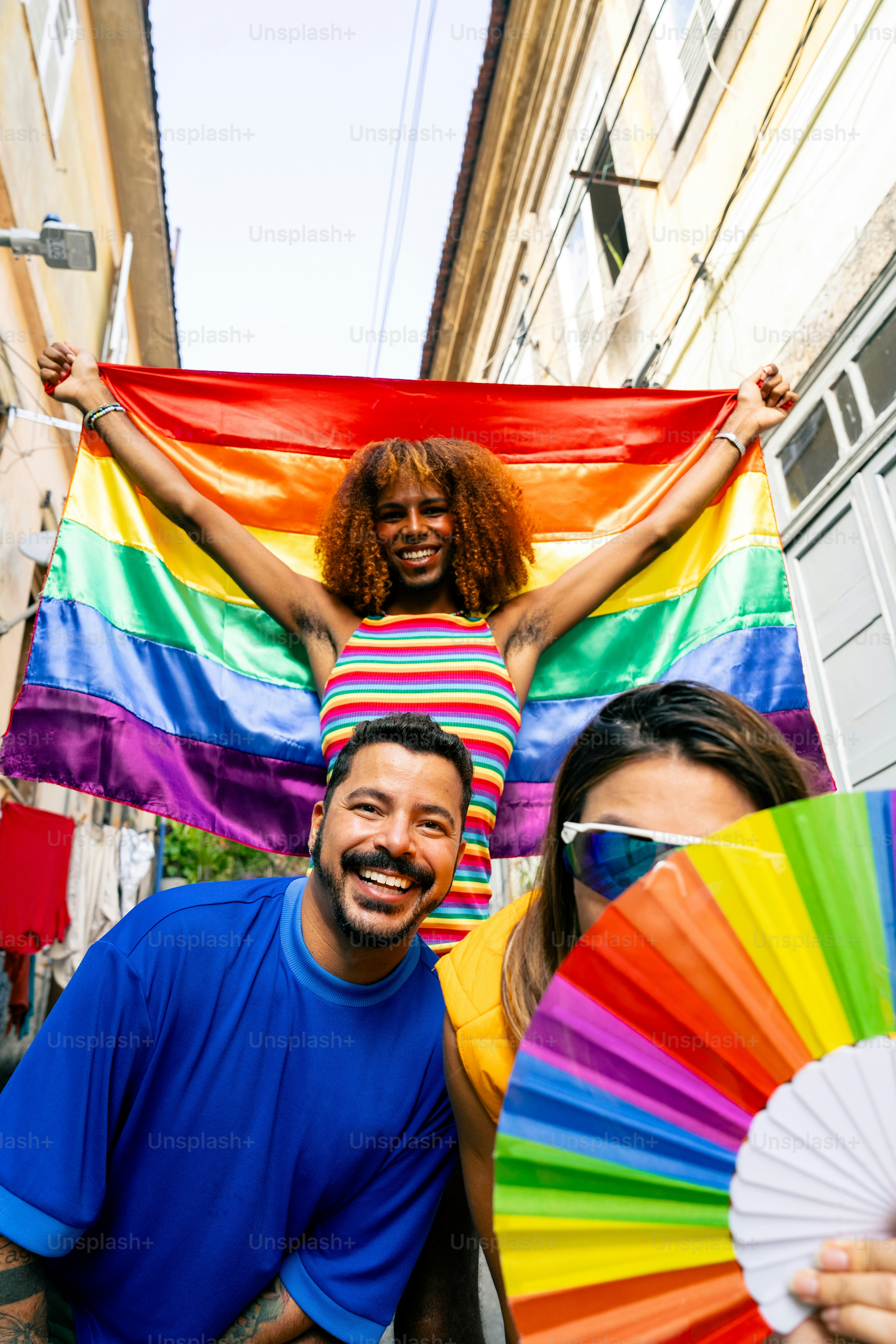 A group of people standing around each other holding a rainbow flag ...