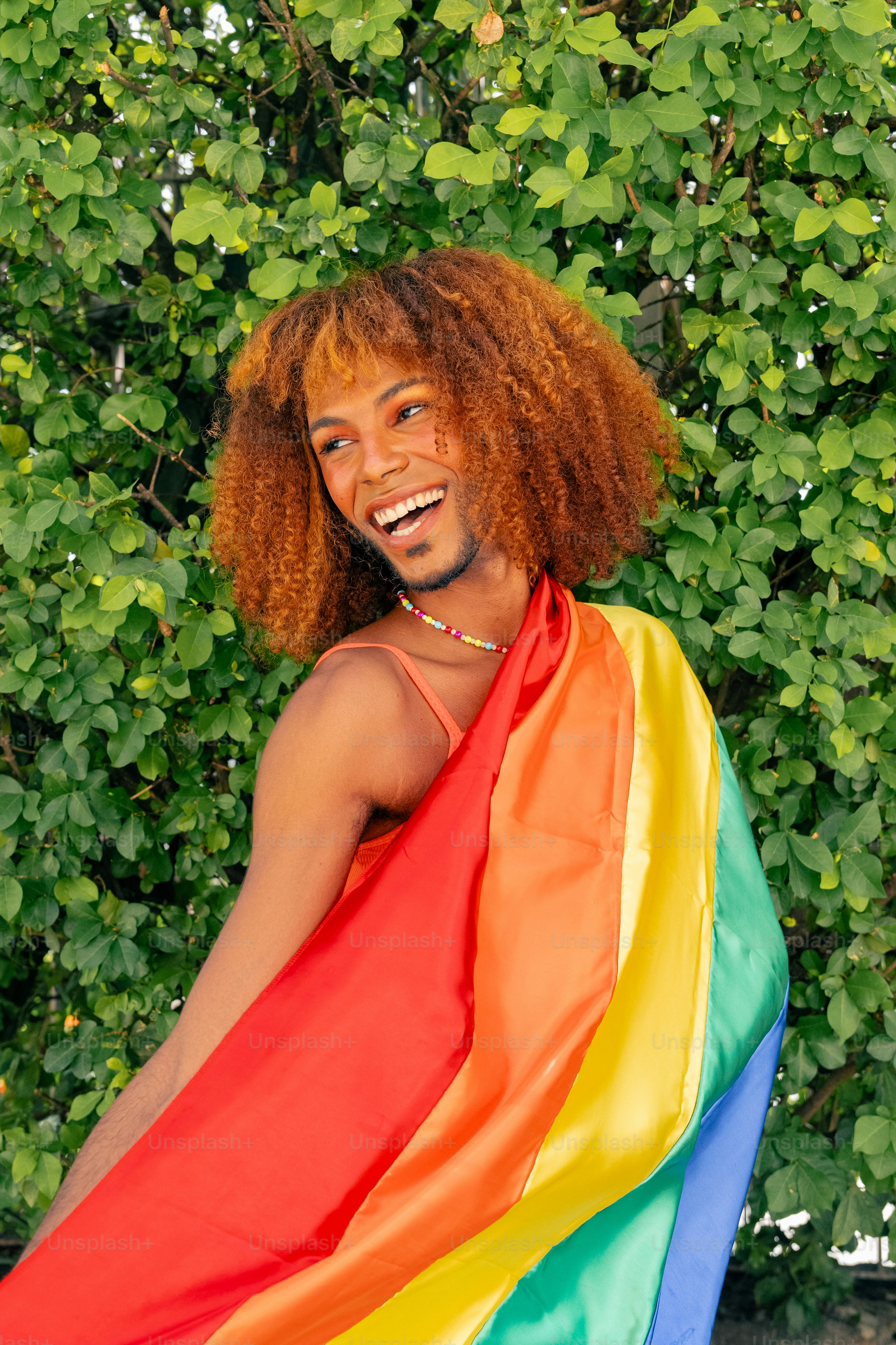 um homem com cabelos ruivos e uma bandeira do arco-íris