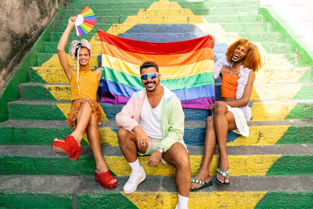 a group of people sitting on steps holding a rainbow flag