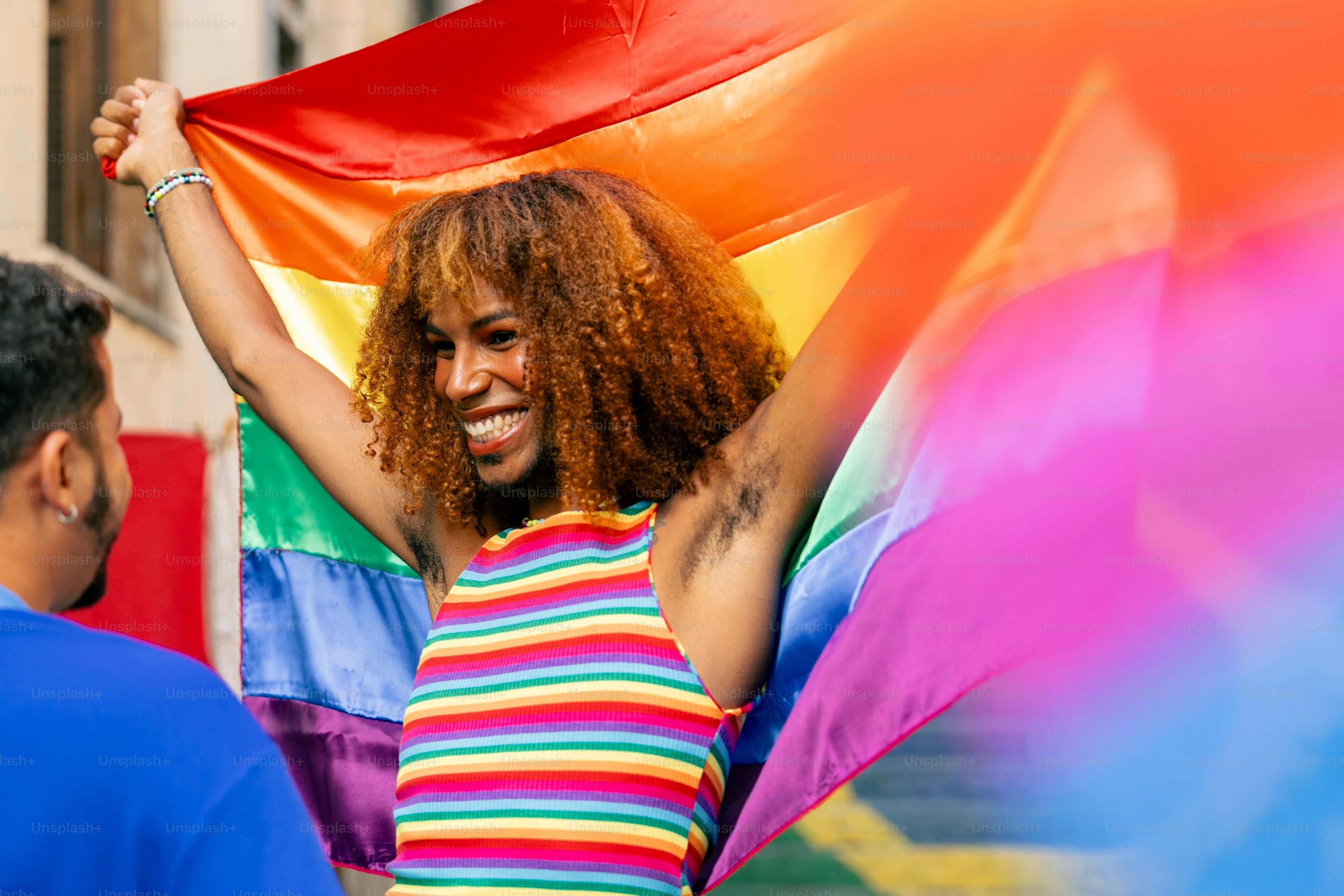 uma mulher segurando uma bandeira do arco-íris em suas mãos