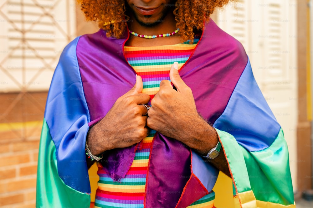 a man wearing a rainbow colored cape and holding a cell phone