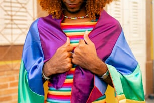a man wearing a rainbow colored cape and holding a cell phone