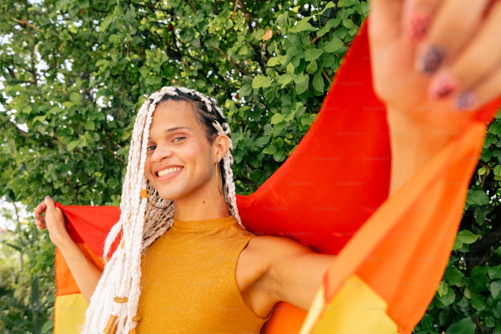 a woman with dreadlocks holding an orange and yellow scarf