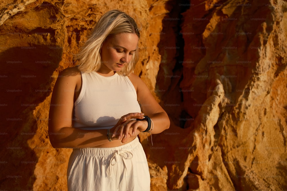 a woman standing in front of a rock wall using a cell phone