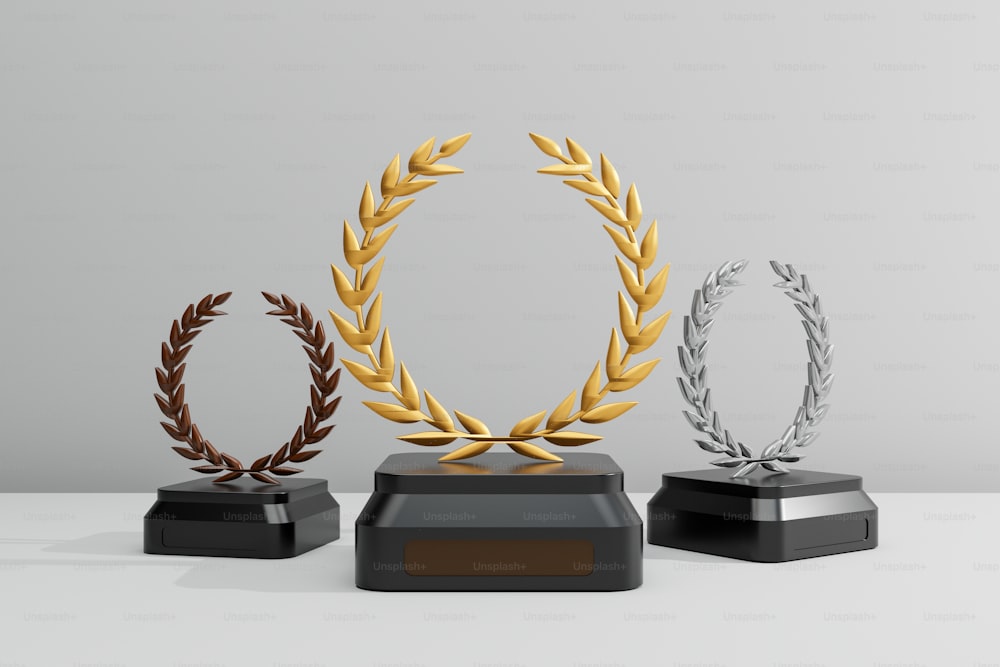 três troféus com decorações de ouro, prata e bronze