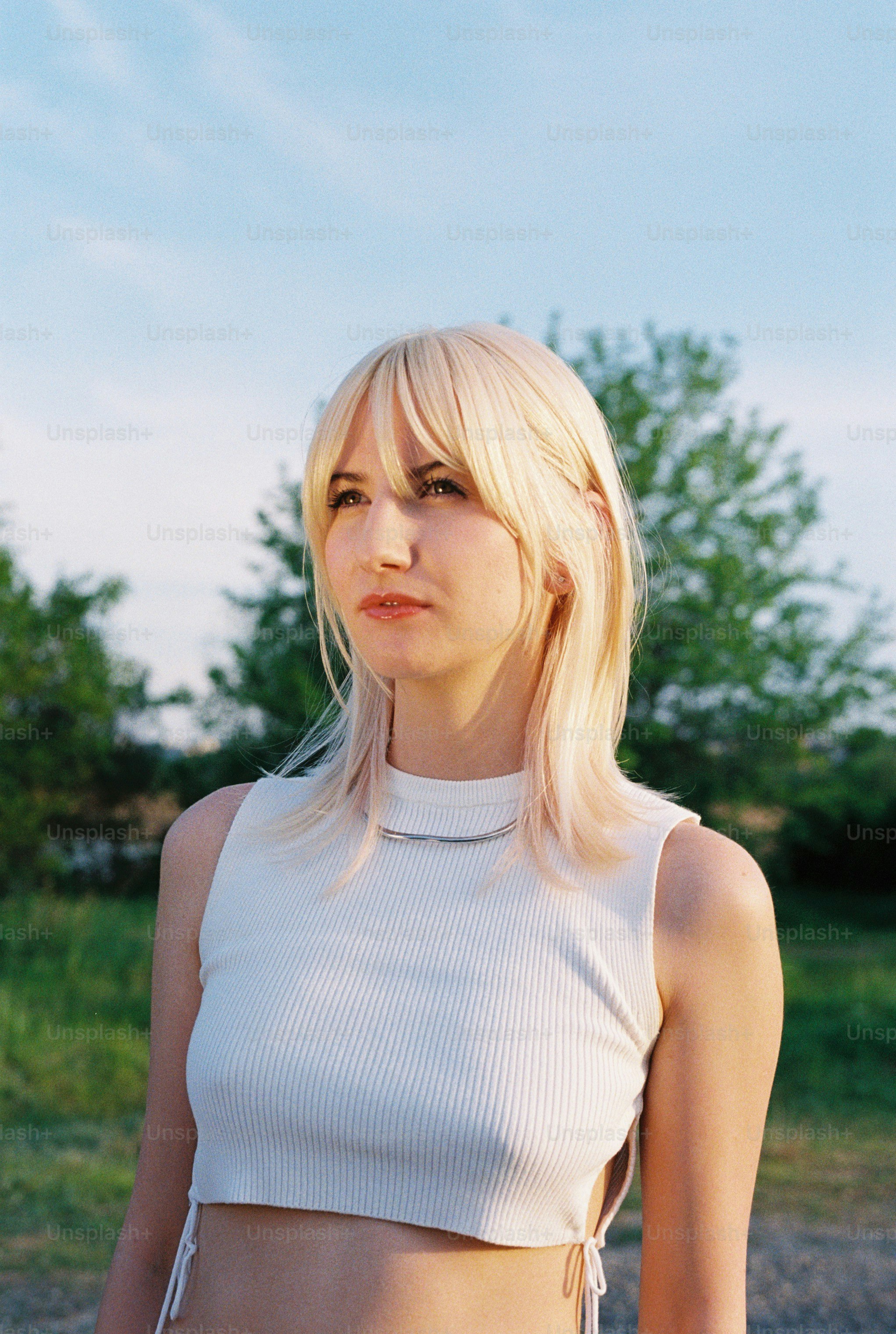 a woman with blonde hair wearing a white top