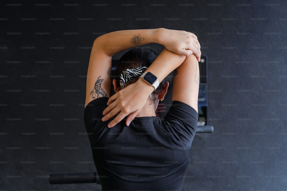 a woman in a black shirt is holding her arms behind her head