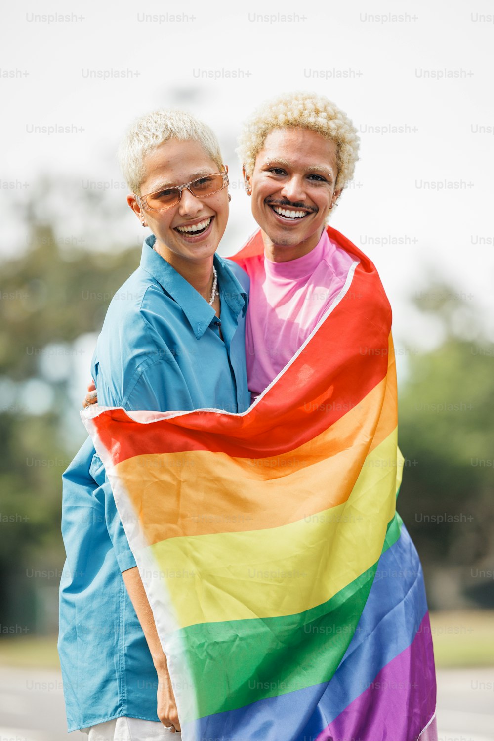 Un par de mujeres de pie una al lado de la otra sosteniendo una bandera arcoíris