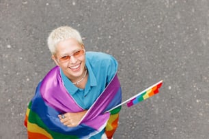 Una mujer con una camisa azul sosteniendo una bandera arcoíris