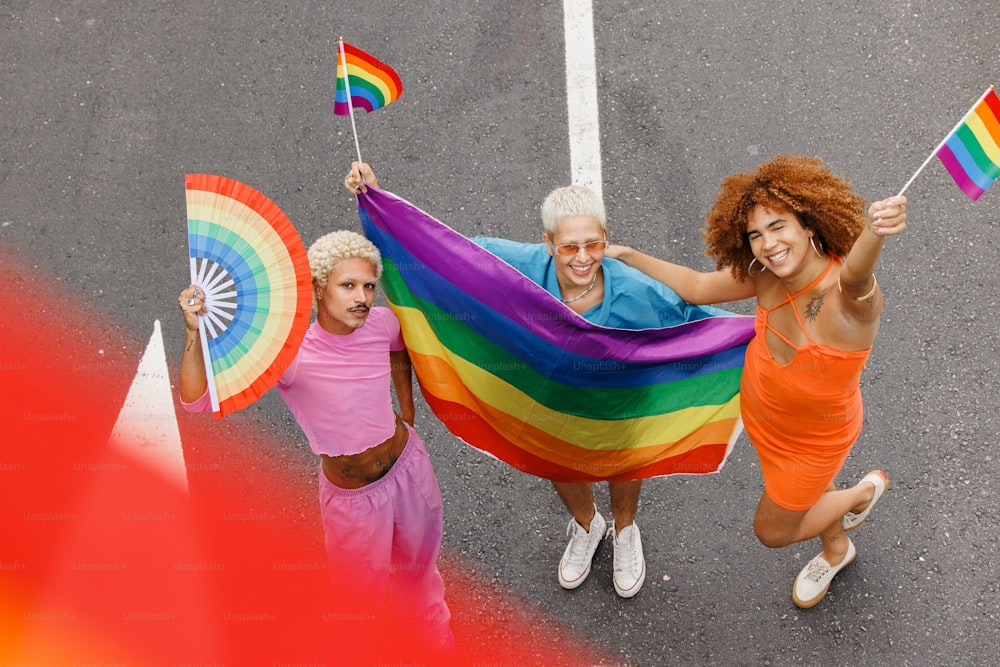 Tres mujeres sosteniendo banderas arcoíris y sonriendo