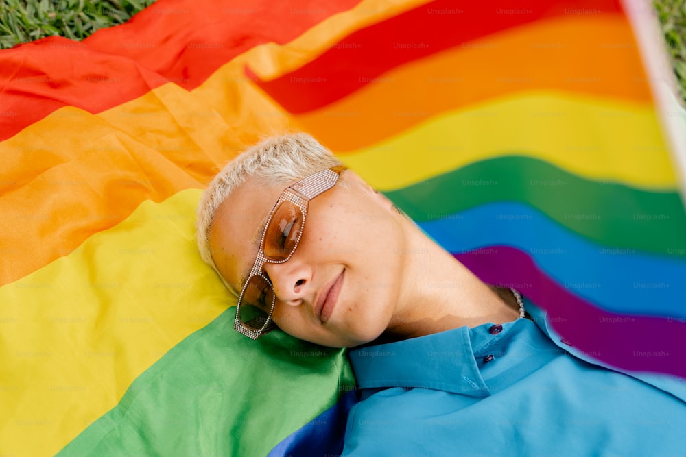 uma pessoa deitada na grama com uma bandeira do arco-íris
