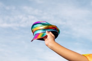 Eine Person hält einen bunten Hut in die Luft