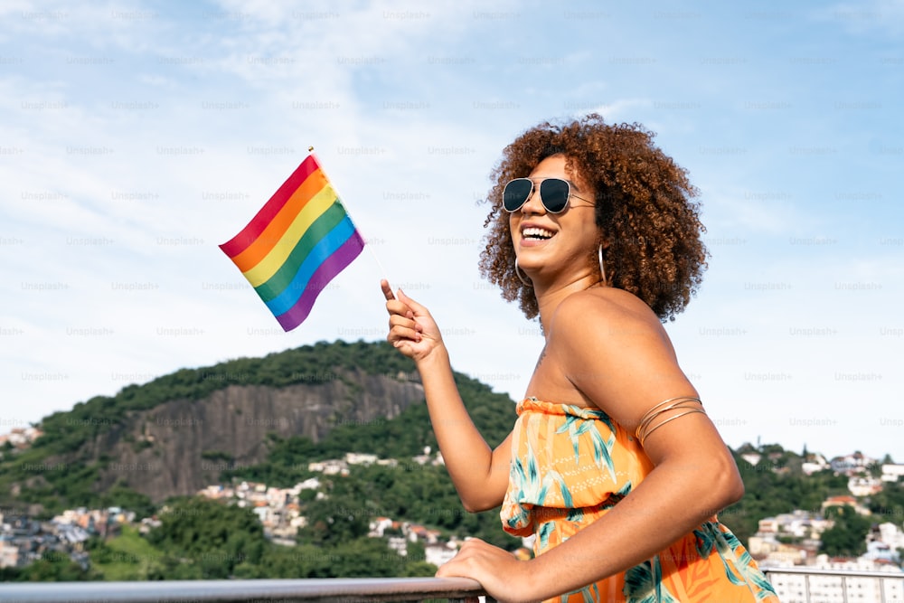 a woman in a dress holding a rainbow flag