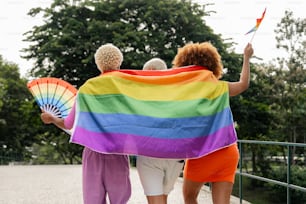 um grupo de mulheres caminhando por uma rua segurando uma bandeira do arco-íris