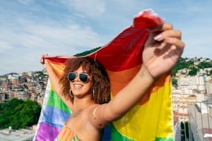 uma mulher em um biquíni segurando uma bandeira do arco-íris