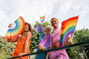 um grupo de pessoas ao lado um do outro segurando guarda-chuvas arco-íris