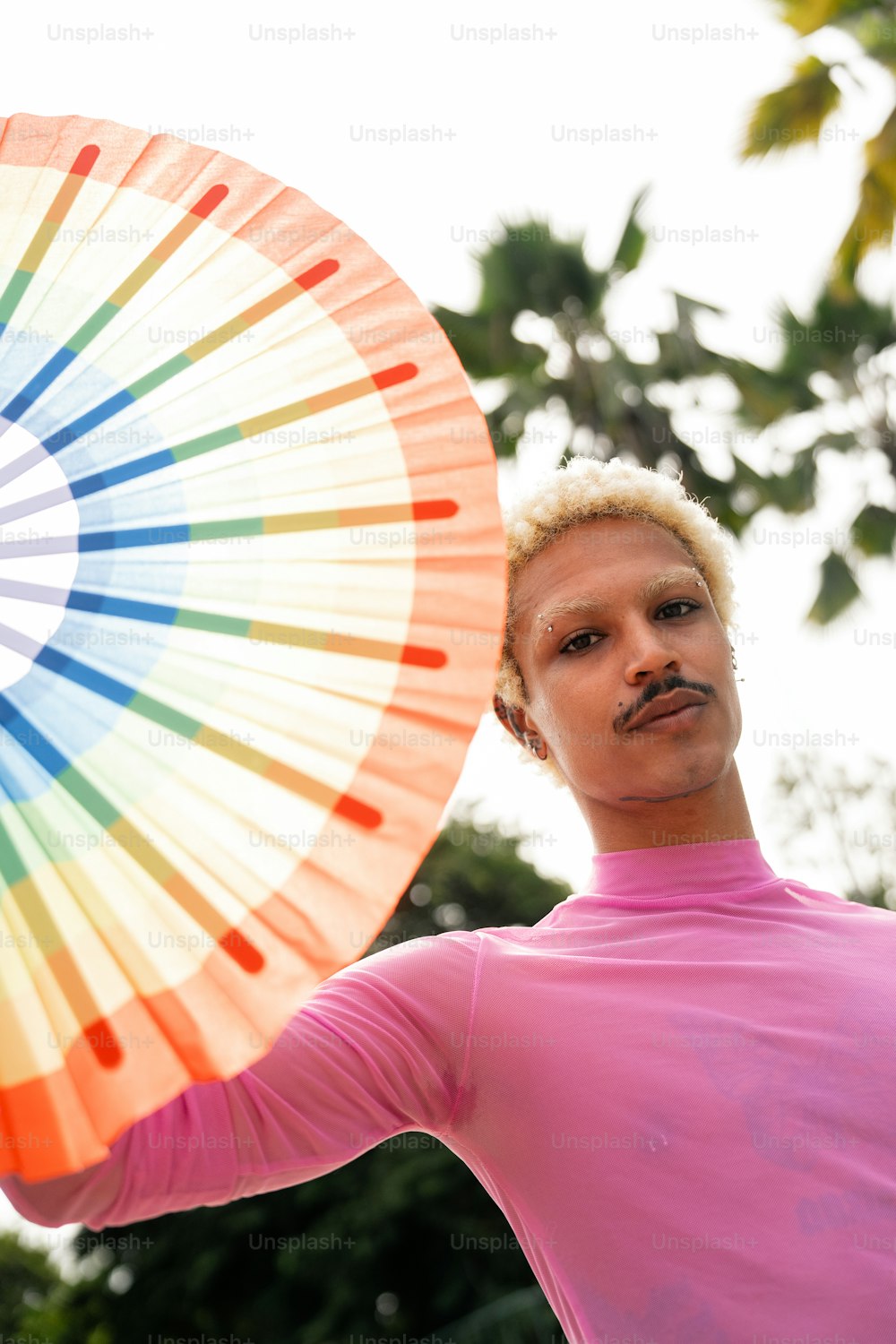 a man in a pink shirt holding a colorful umbrella