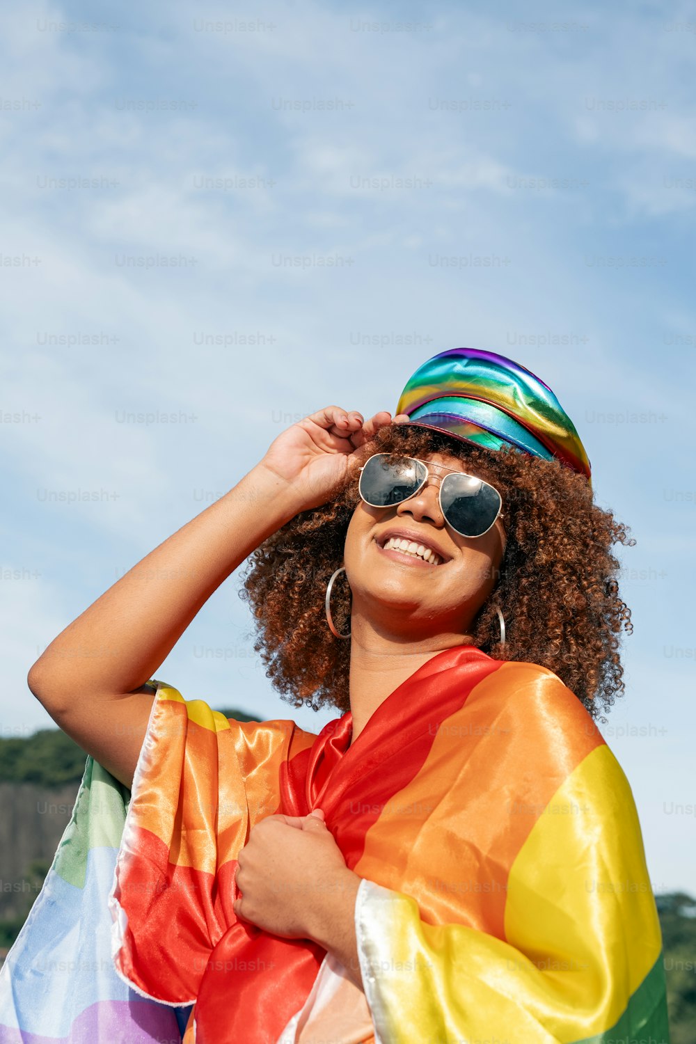 une femme portant une écharpe aux couleurs de l’arc-en-ciel et des lunettes de soleil