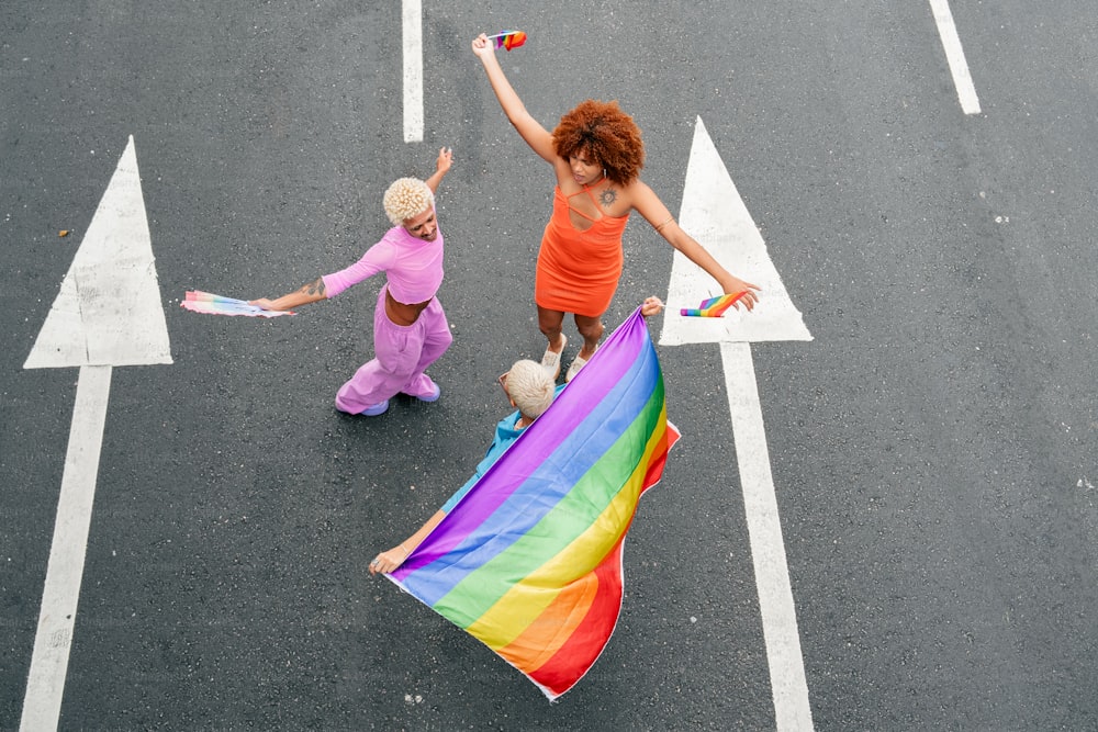 two women walking down a street holding a rainbow flag