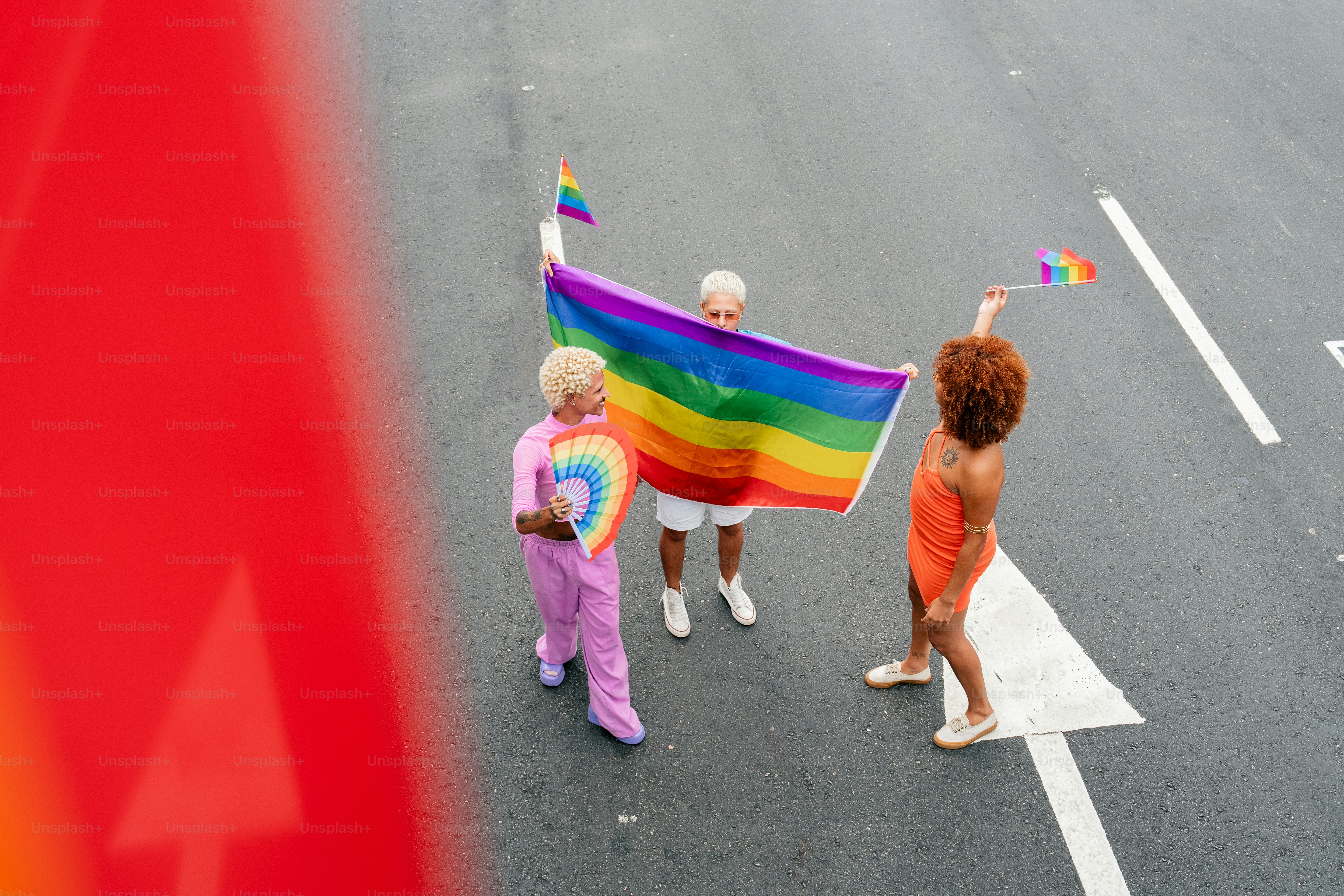 a group of people walking down a street holding a rainbow flag