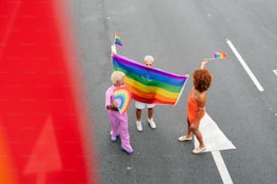 Un grupo de personas caminando por una calle con una bandera arcoíris