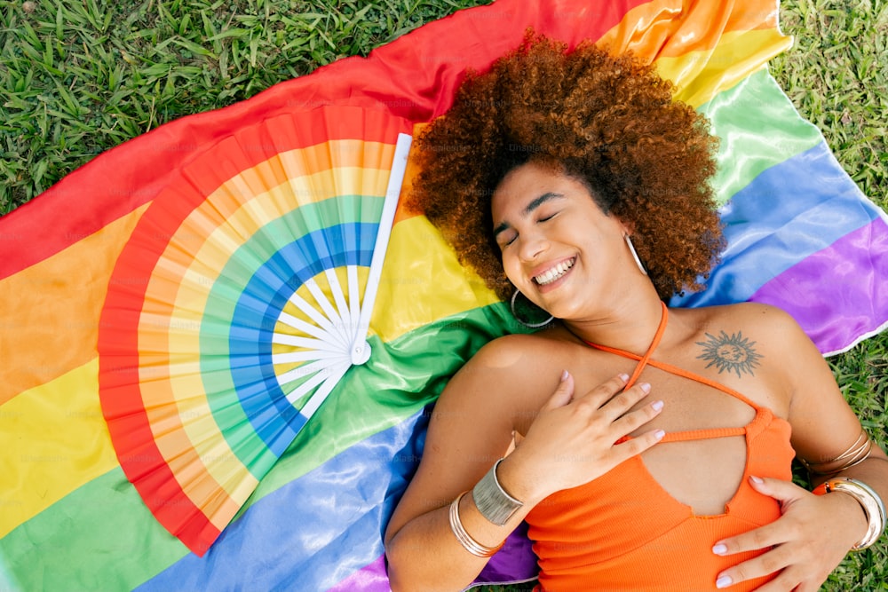 a woman laying in the grass with a rainbow kite