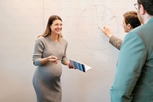 a pregnant woman standing in front of a whiteboard