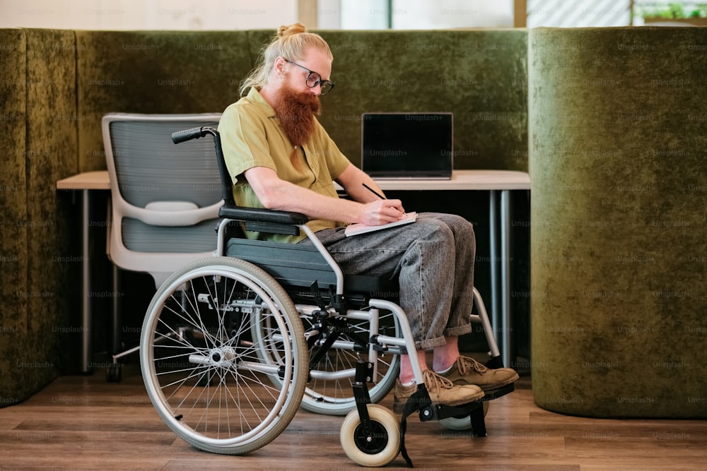 a man sitting in a wheel chair using a laptop