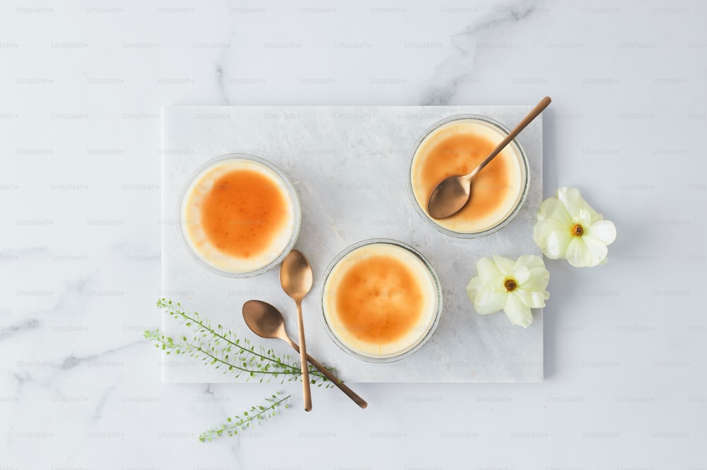 three cups of coffee with spoons on a marble tray