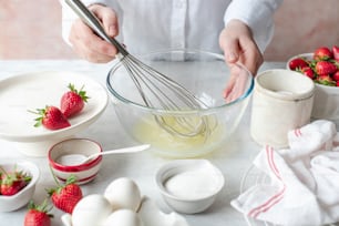 a person whisking eggs and strawberries in a bowl