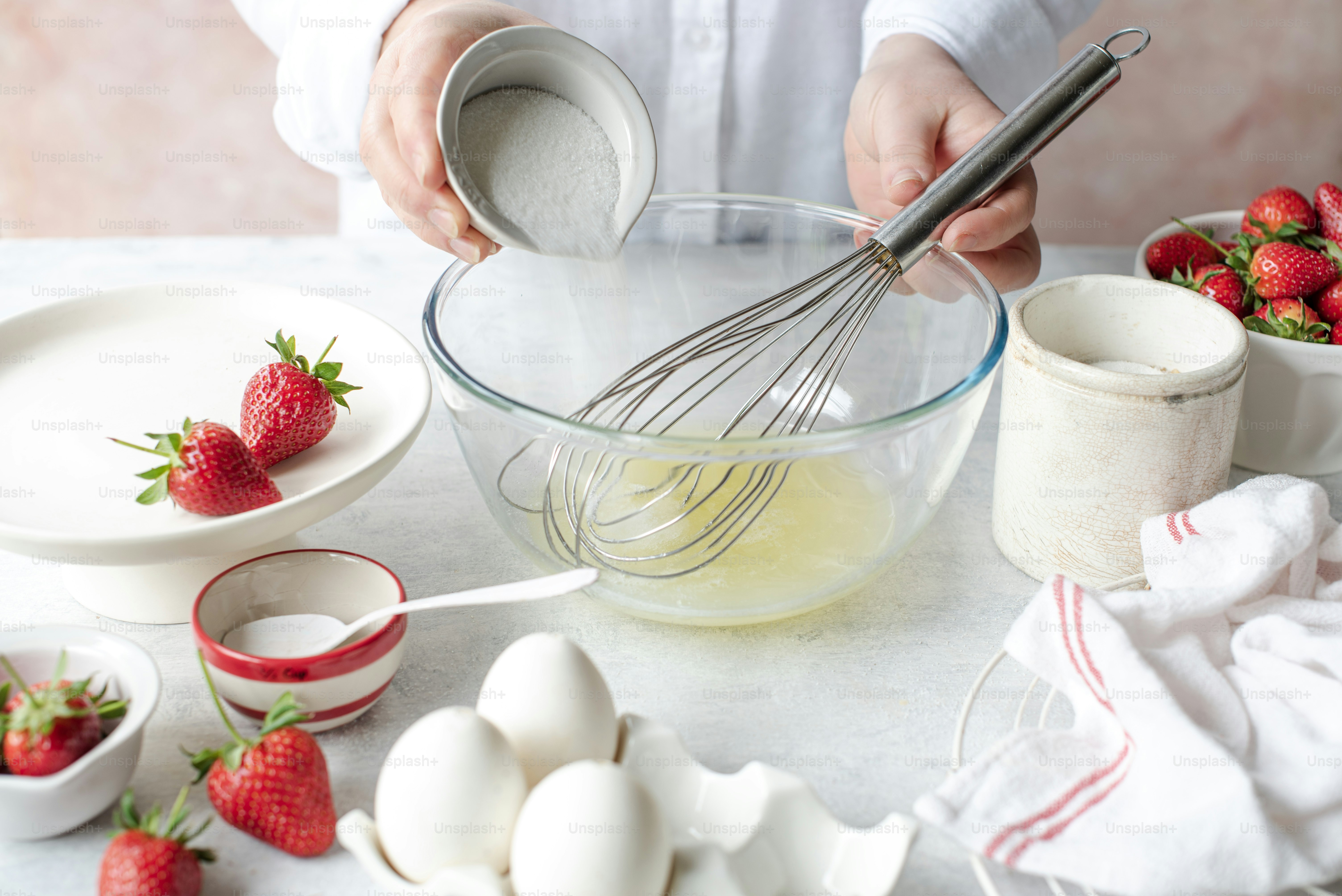 a person whisking eggs and strawberries in a bowl