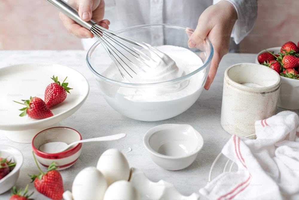 a person whisking eggs and strawberries in a bowl
