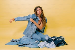 a woman sitting on the ground surrounded by clothes