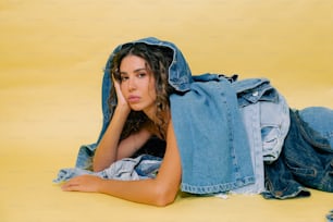 a woman laying on the ground with a jean jacket over her head