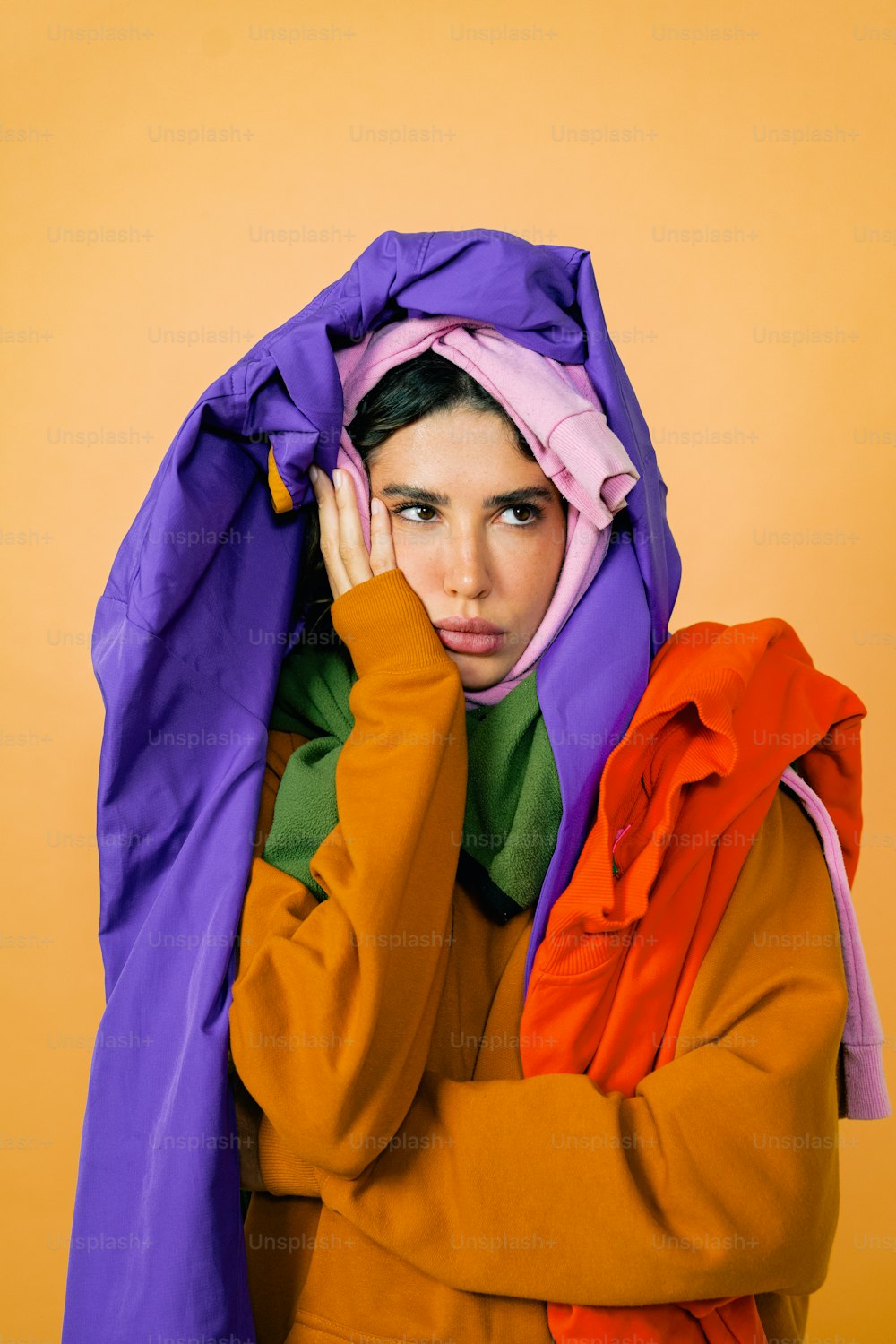 a woman with a purple and orange jacket covering her face